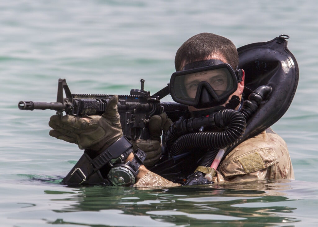 Force Reconnaissance Marine provides security while conducting an amphibious insertion onto a beach