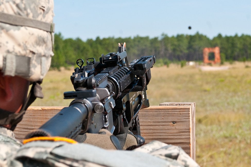 Soldier aiming a rifle with a mounted M320.