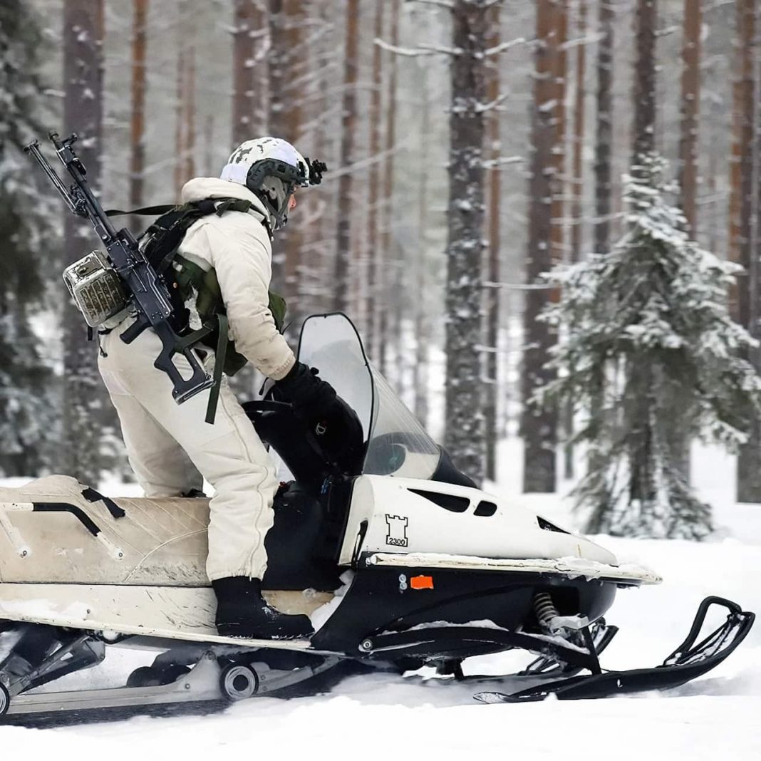 Finnish soldier on a snowmobile and a PKM machine gun during exercise