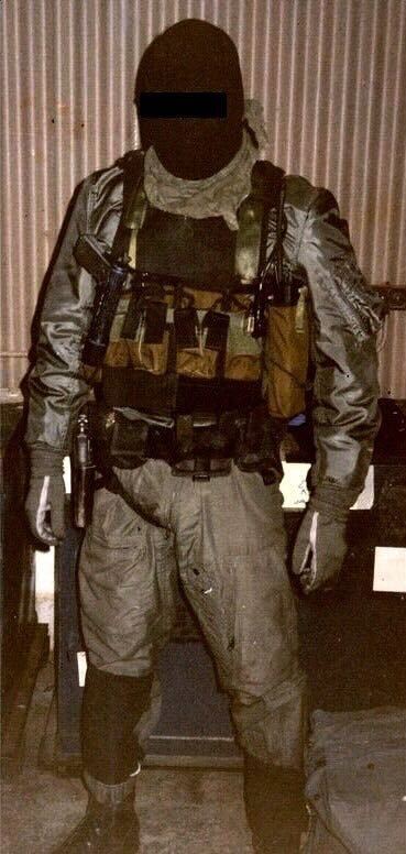 Delta operator in a flight suit and combat gear with two pistols and a censored face.