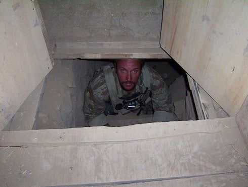 Soldier peeking out of an underground tunnel.