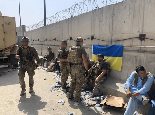 Ukraine soldiers standing behind concrete wall with Ukrainian flag.