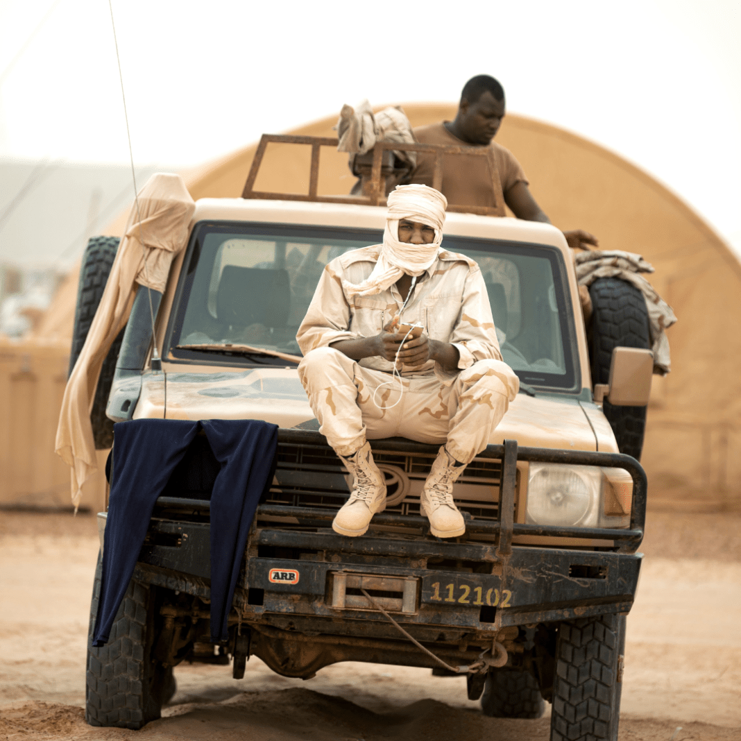 A Mauritanian Special Forces soldier observes from the hood of a military vehicle while other soldiers practice weapons handling skills at the Nouakchott camp where Western and African partners stay during FLINTLOCK 20 in Nouakchott, Mauritania, February 17, 2020.