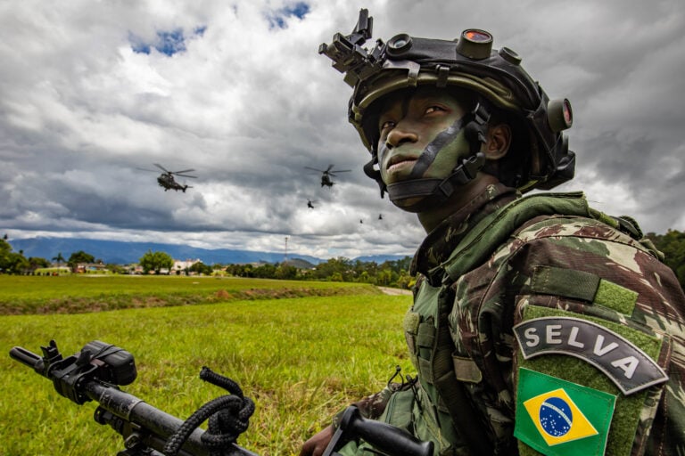 A Brazilian army soldier assigned to 5th Battalion, 12th Light Infantry (Air Assault), 2nd Division, kneels in the grass during Southern Vanguard 22 in Lorena, Brazil, Dec. 7, 2021.