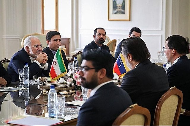 Venezueln and Iranian Diplomats sit on a table to discuss bilateral issues.