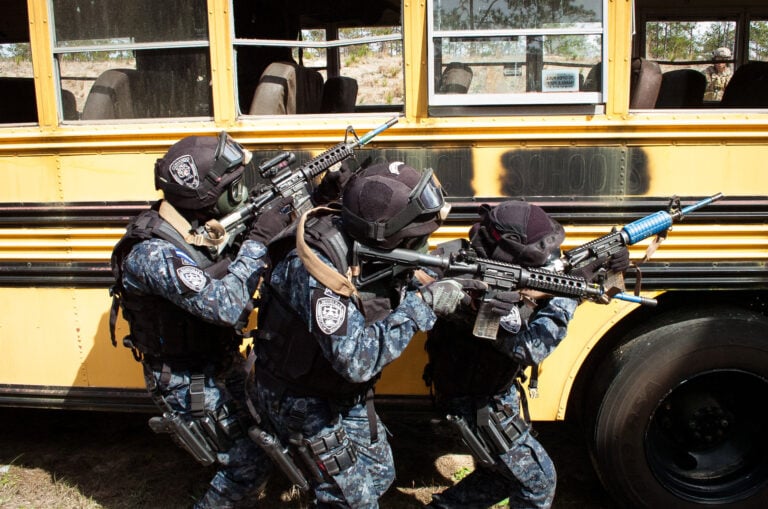 Honduran TIGRES clear along the side of a school bus used as a training aid located on an Eglin Air Force Base range