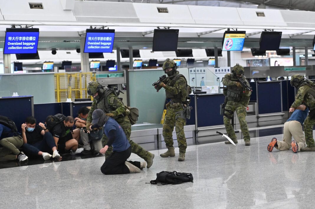 Four SDU operators apprehend two people acting as terrorist suspects in an airport check in area. While actors playing shocked civilians sit on the floor. This is part of a demonstration by the police for the press.