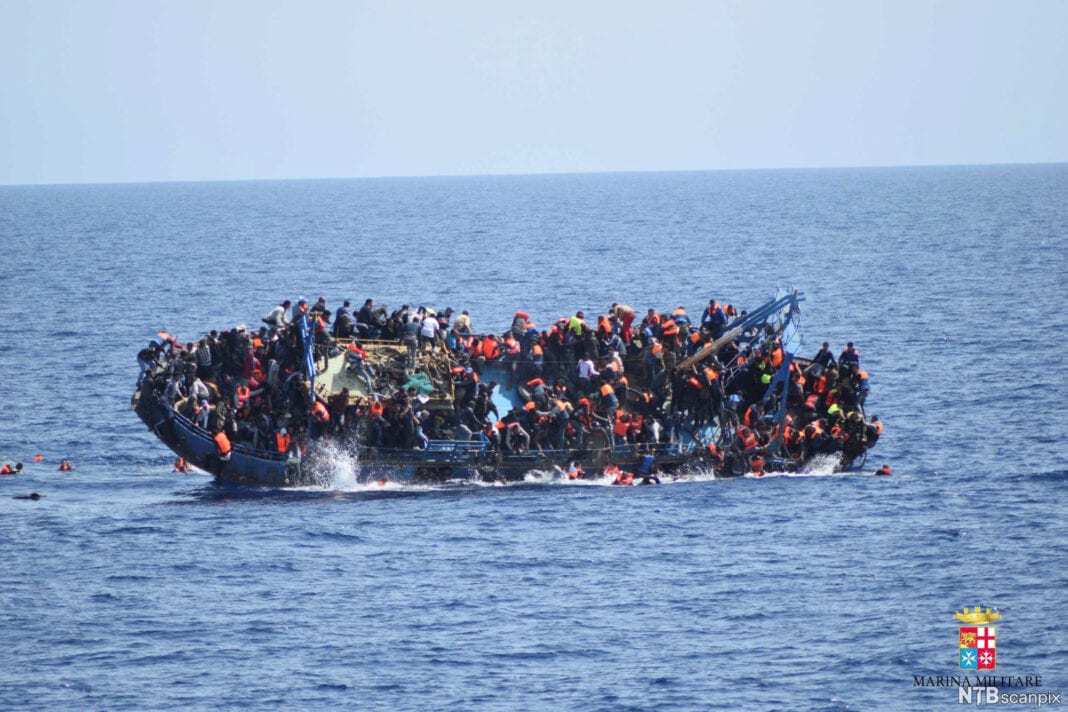 Migrants are seen on a capsizing boat before a rescue operation by Italian navy ships Bettica and Bergamini