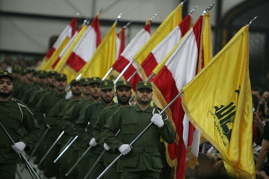 Hezbollah soldiers with Hezbollah and Lebanese flags in a parade.