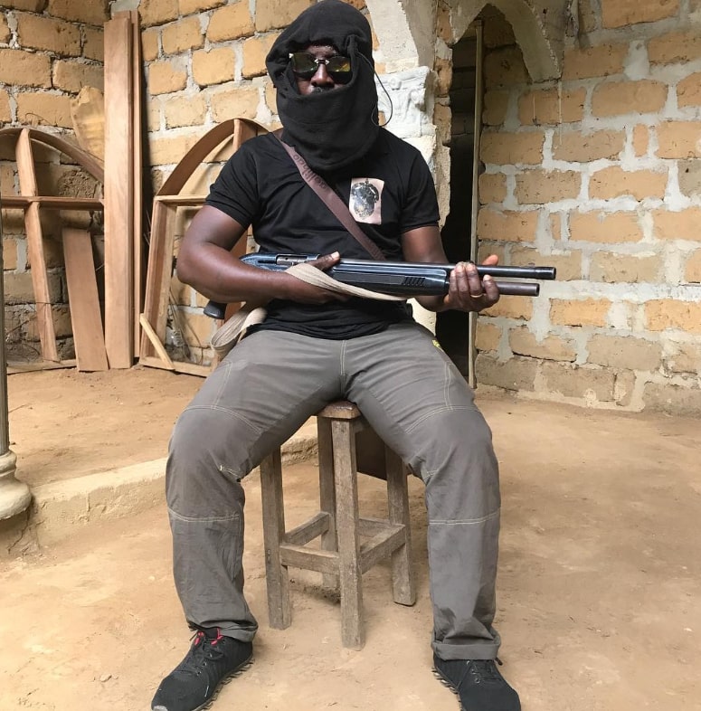 An Amba Boy affliated with the Ambazonia Military Forces (AMF) is photographed with a pump-action rifle.