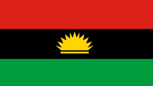 The Biafran flag. Three horizontal colours in order of red, black, and green. A yellow sun is depicted in the centre.