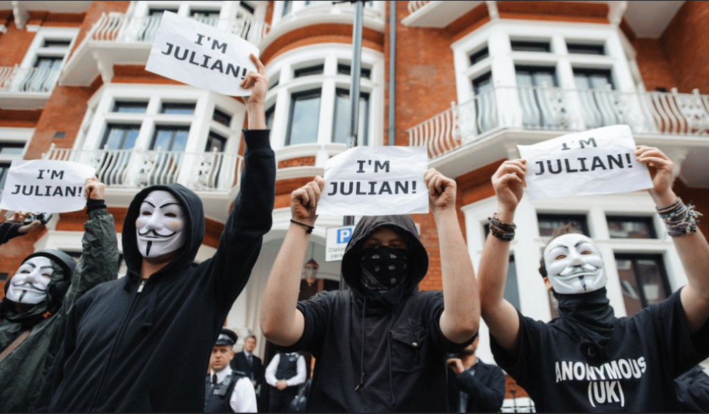 Anonymous UK members photographed holding placards which read: 'I'm Julian'