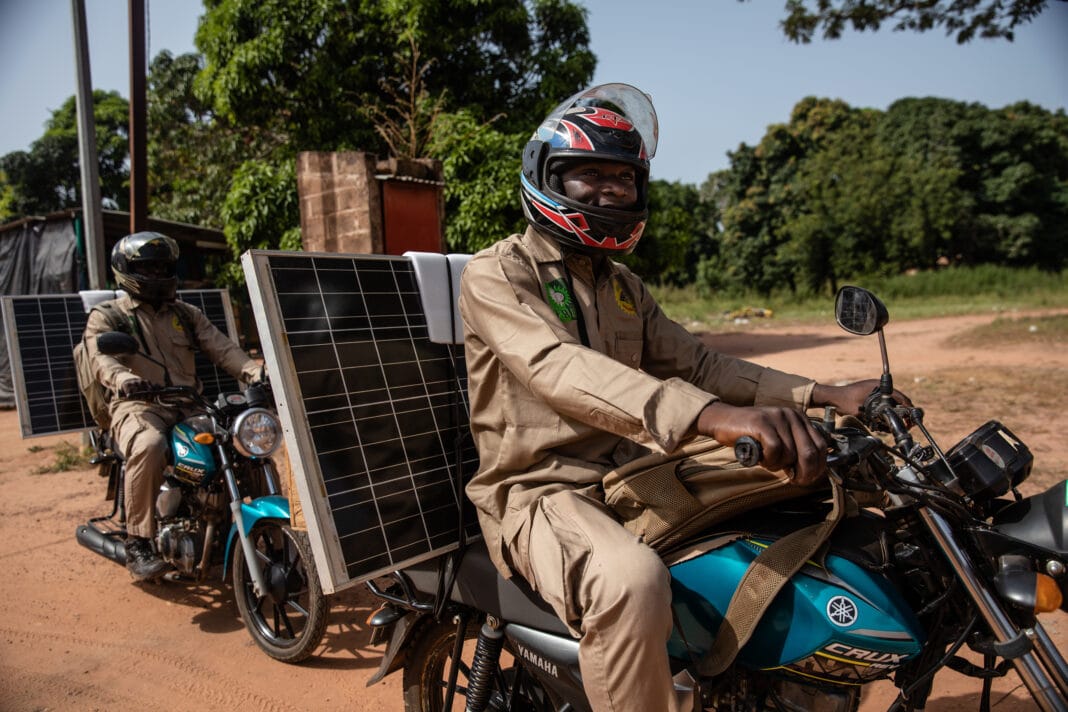 Men on motorcycles delivering solar panels as a part of the Yeleen program in Burkina Faso