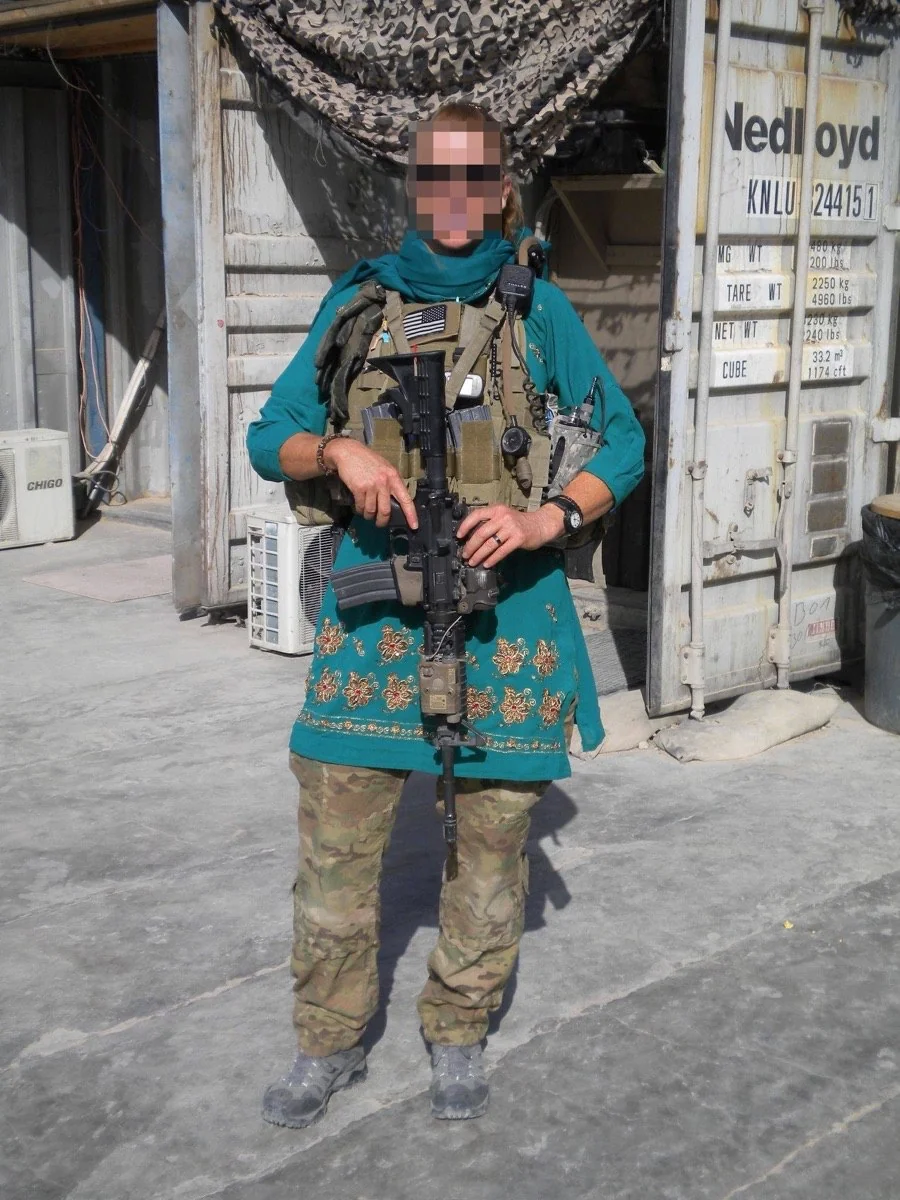 U.S. Cultural Support Team member in Afghanistan wearing a teal embroidered Afghan tunic over body armour and combat trousers, rifle held at the ready.